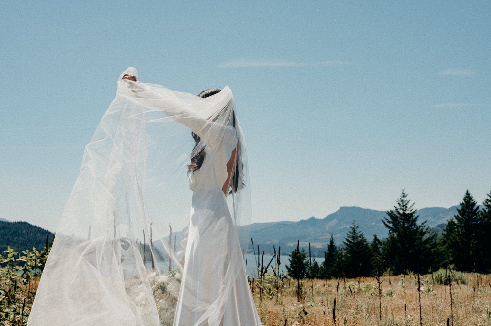 A bride plays with her veil at Wind Mountain Ranch in the Columbia River Gorge. Taken by fine art Oregon wedding photographer Briana Morrison