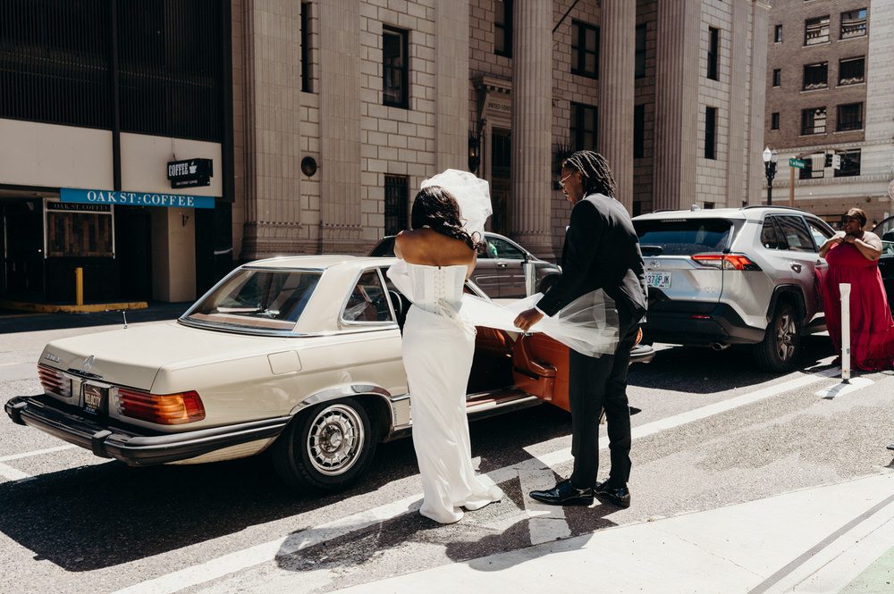 Oregon wedding photographer captures a candid portrait of a bride and groom getting in a vintage car.