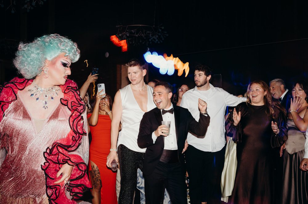 Two grooms party with their guests while a drag queen performs during their reception. Photographed by Oregon wedding photographer, Briana Morrison.