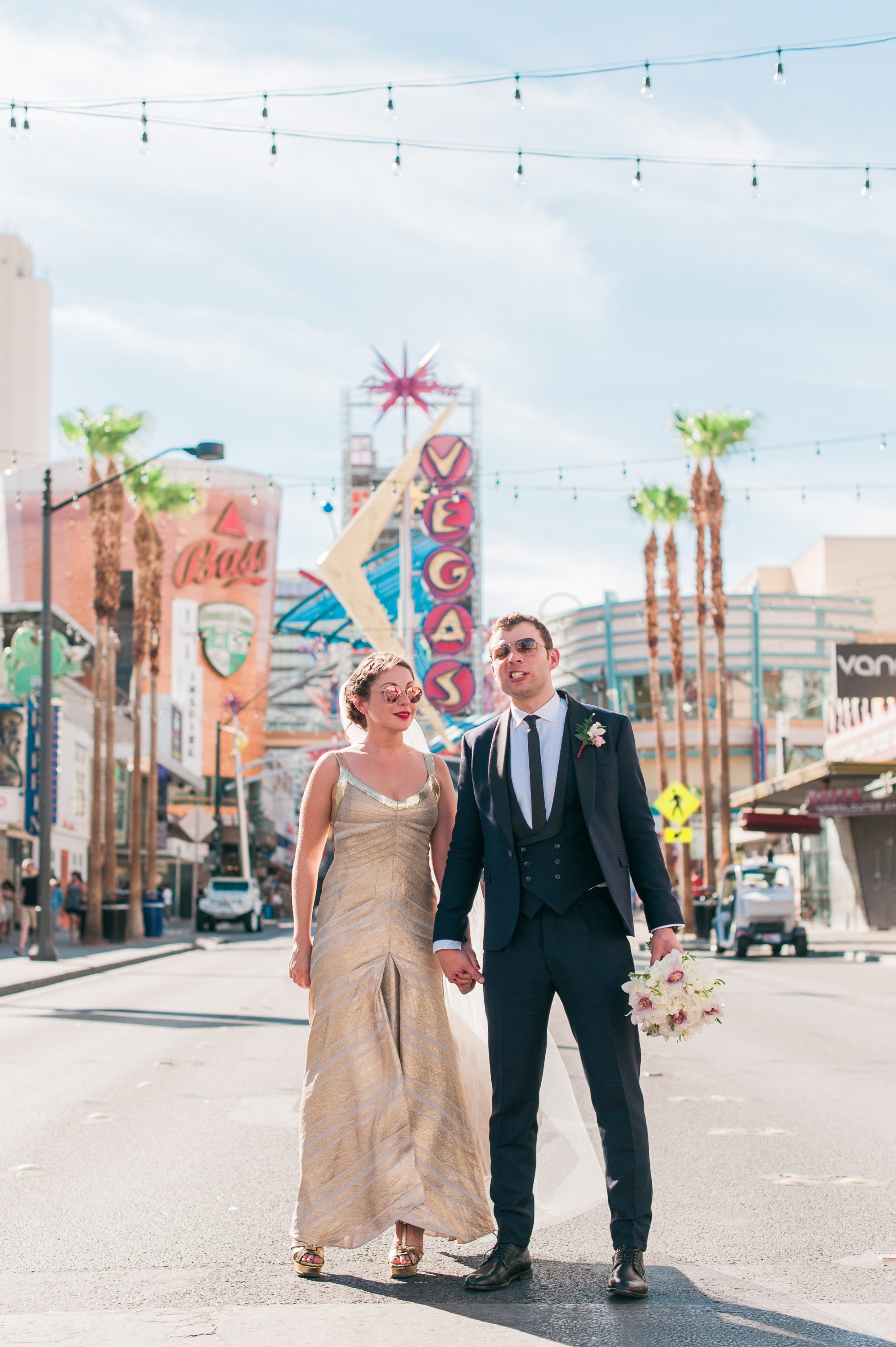 A bride and groom pose in front of a retro Vegas sign in Las Vegas, Nevada. Captured by Las Vegas Elopement Photographer Briana Morrison