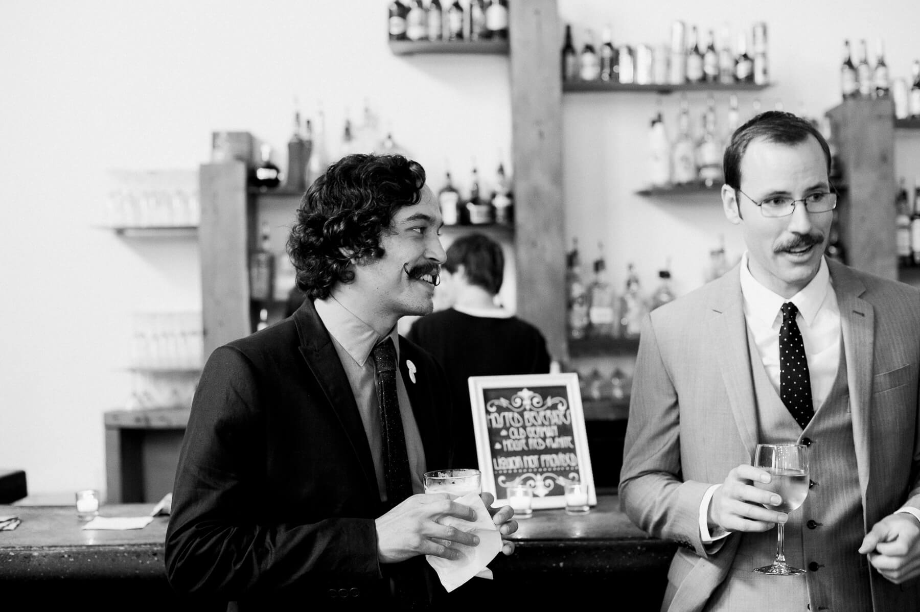 Two groomsmen drinking cocktails before a wedding ceremony at Holocene in Portland, Oregon. By Portland Holocene wedding photographer Briana Morrison