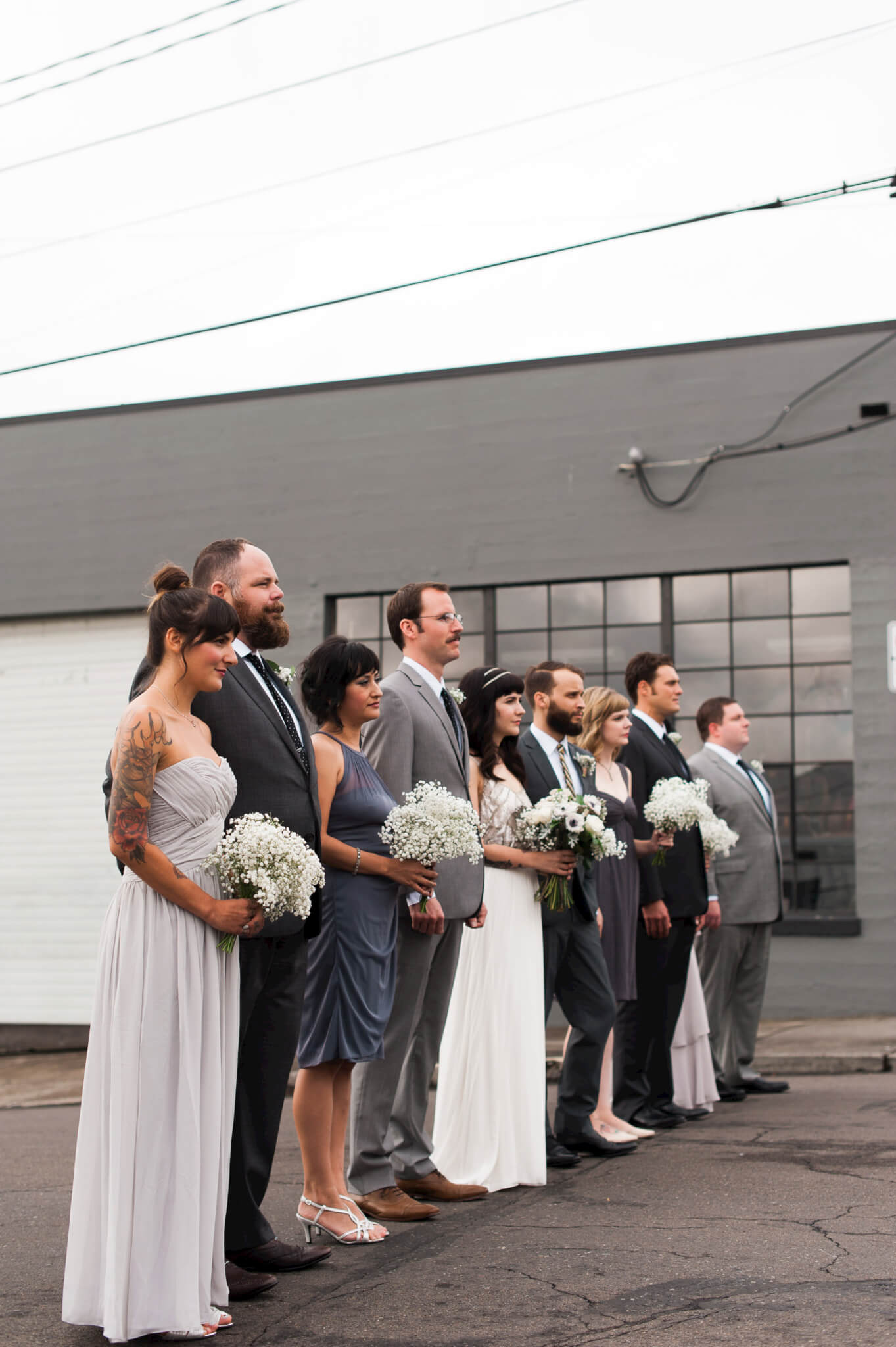 A beautiful wedding party poses on a street in industrial Portland, Oregon. 