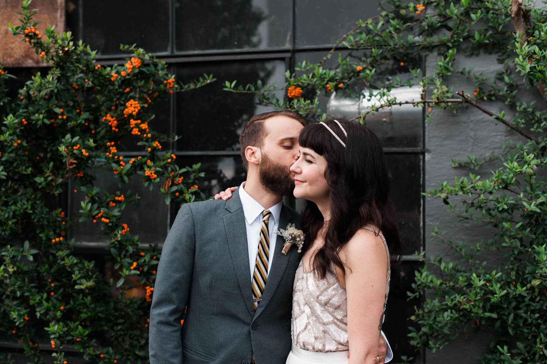 A groom kisses his bride on the cheek in Portland, Oregon. By Portland Holocene Photographer Briana Morrison