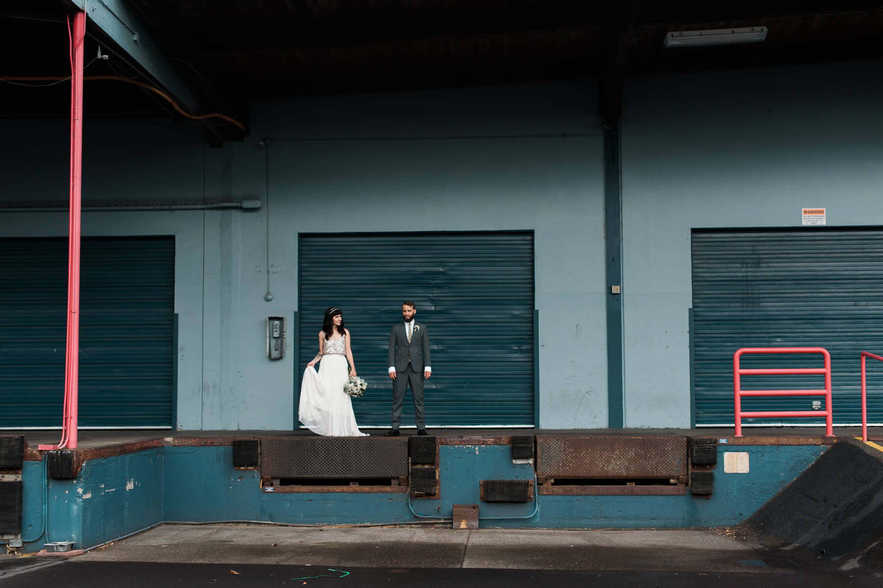 A hip Portland bride and groom pose in a loading dock. By Portland Holocene Photographer Briana Morrison