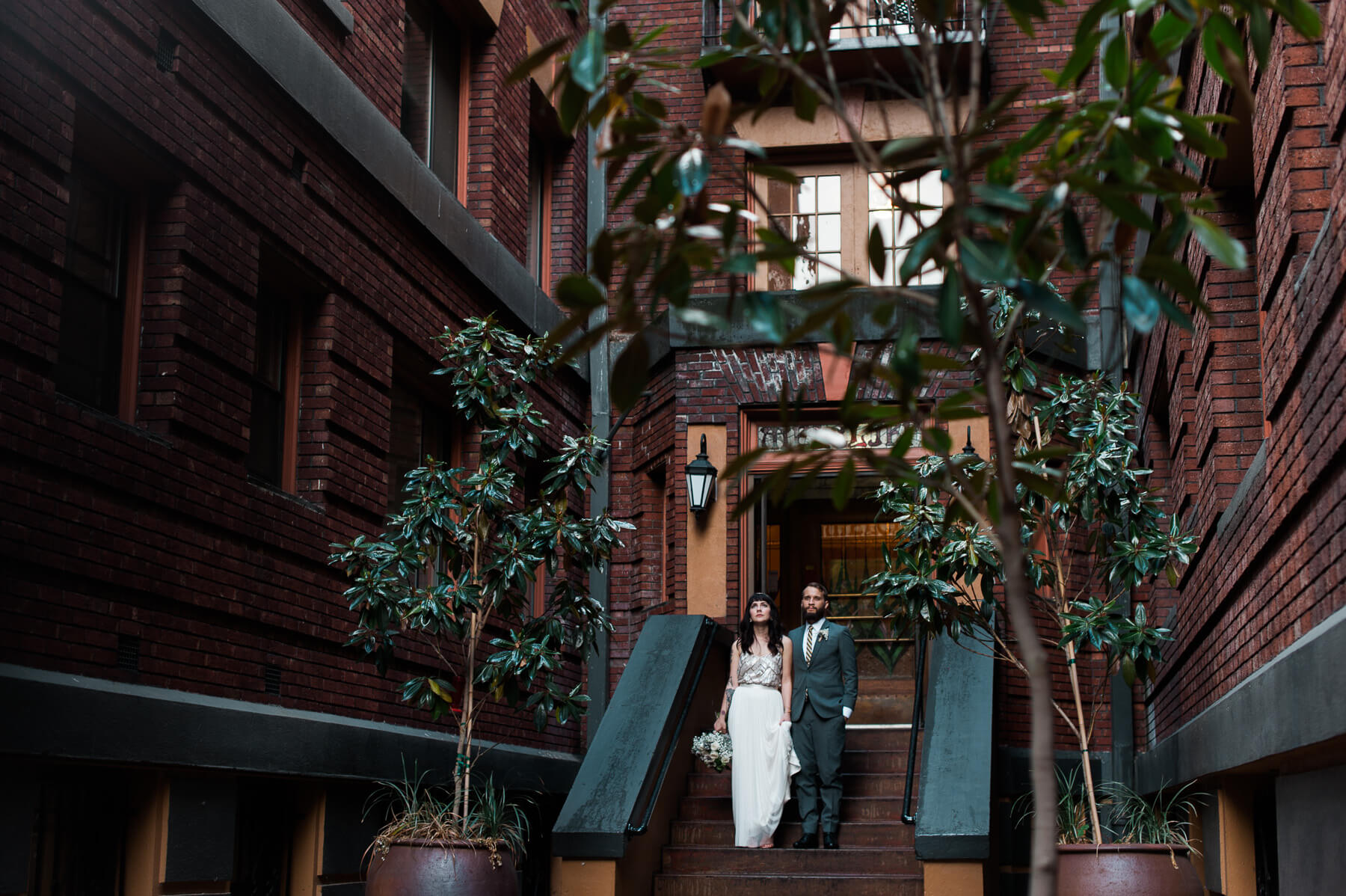 A bride and groom pose in one of Portland's beautiful old apartment courtyards. Photography by Portland Wedding Photographer Briana Morrison