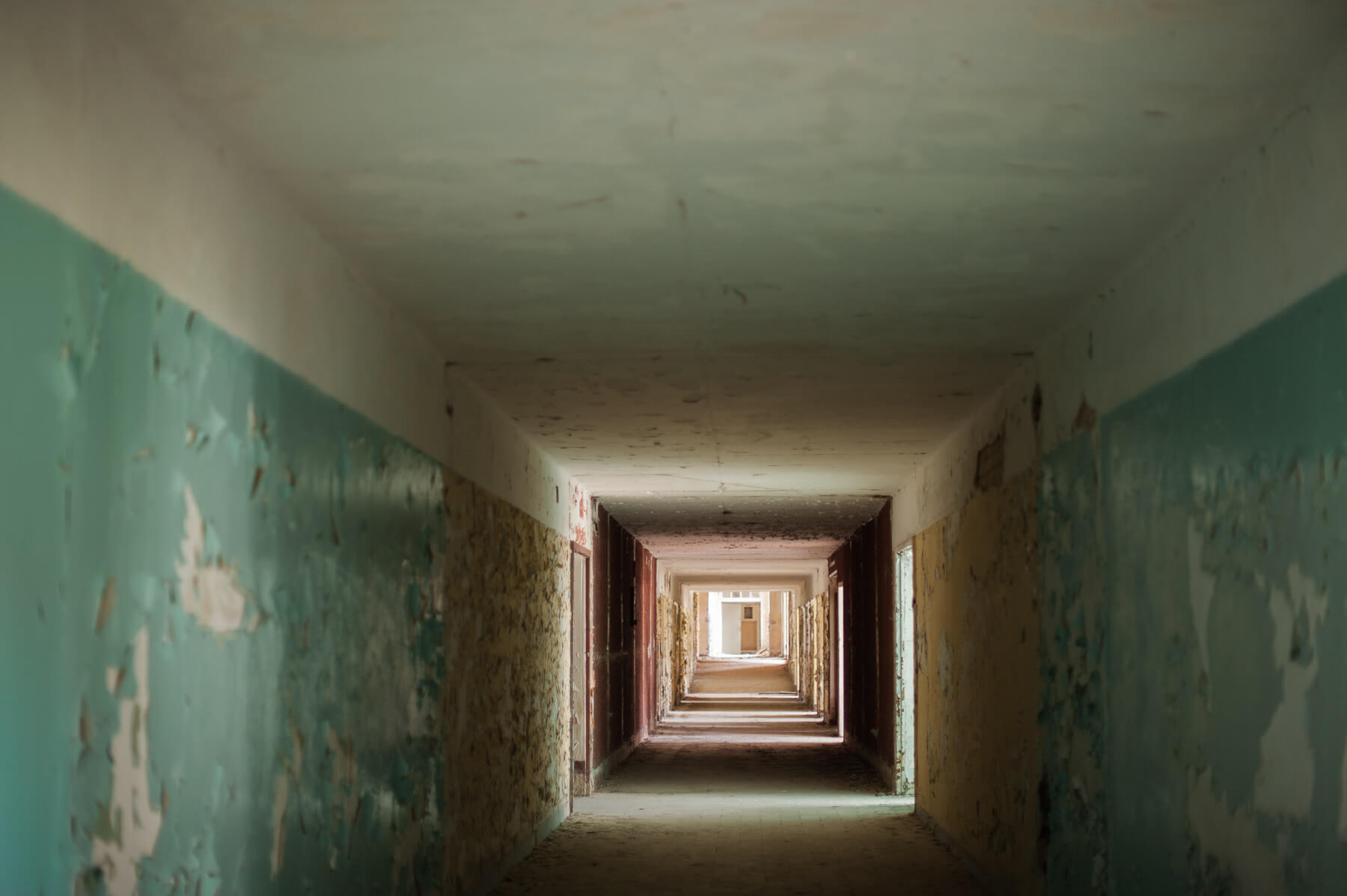 A long hallway inside the abandoned Heilstätten Hohenlychen Sanatorium in Lychen, Germany. Photographs by Berlin Portrait Photographer Briana Morrison