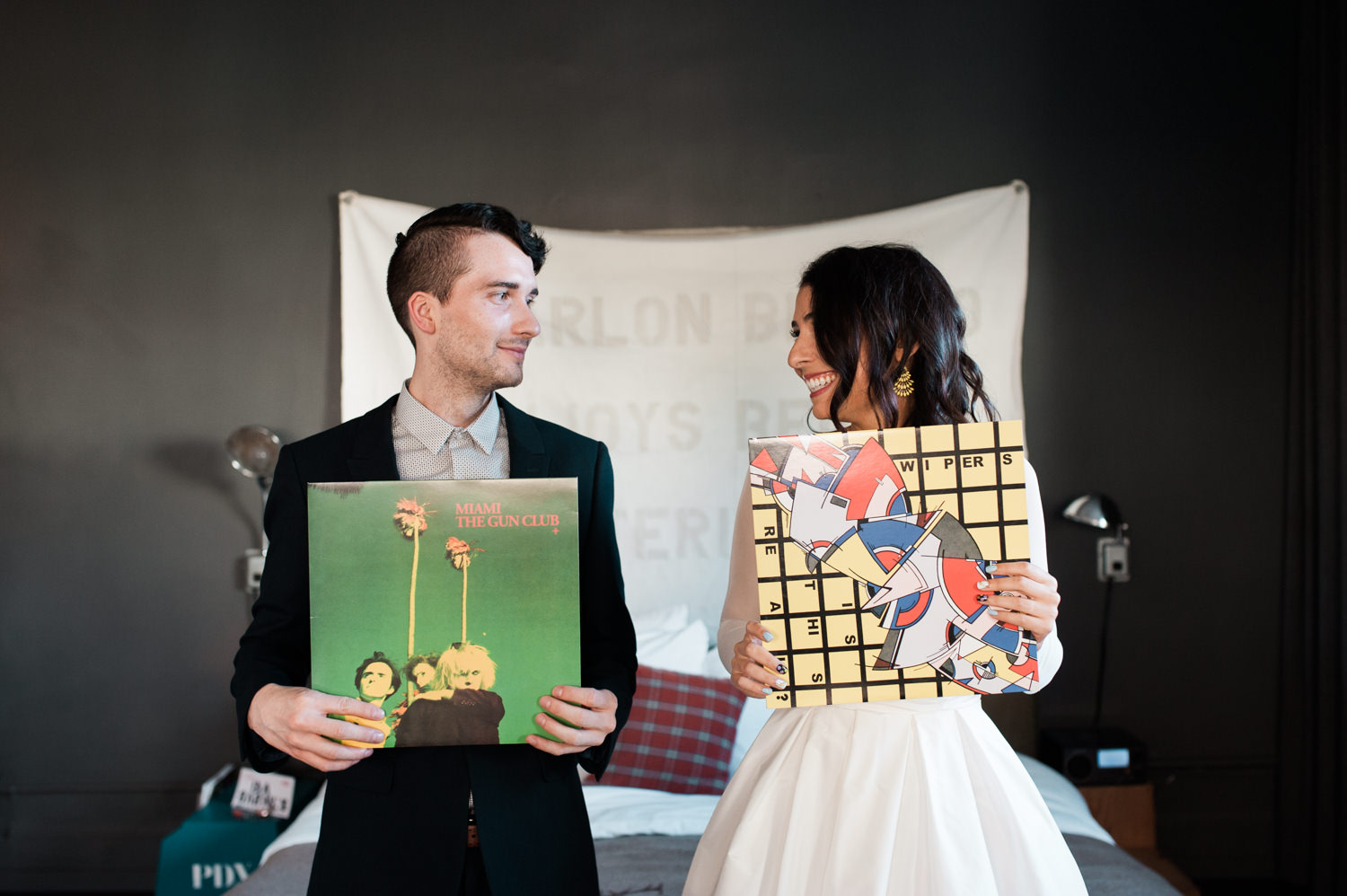 The bride and groom smile at each other from behind their favorite records. by Briana Morrison