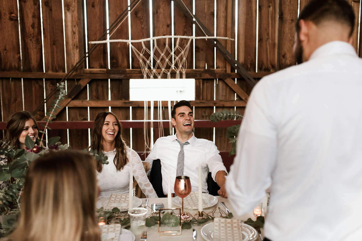The bride and groom react happily to a toast given by the best man. By West Coast wedding photographer Briana Morrison
