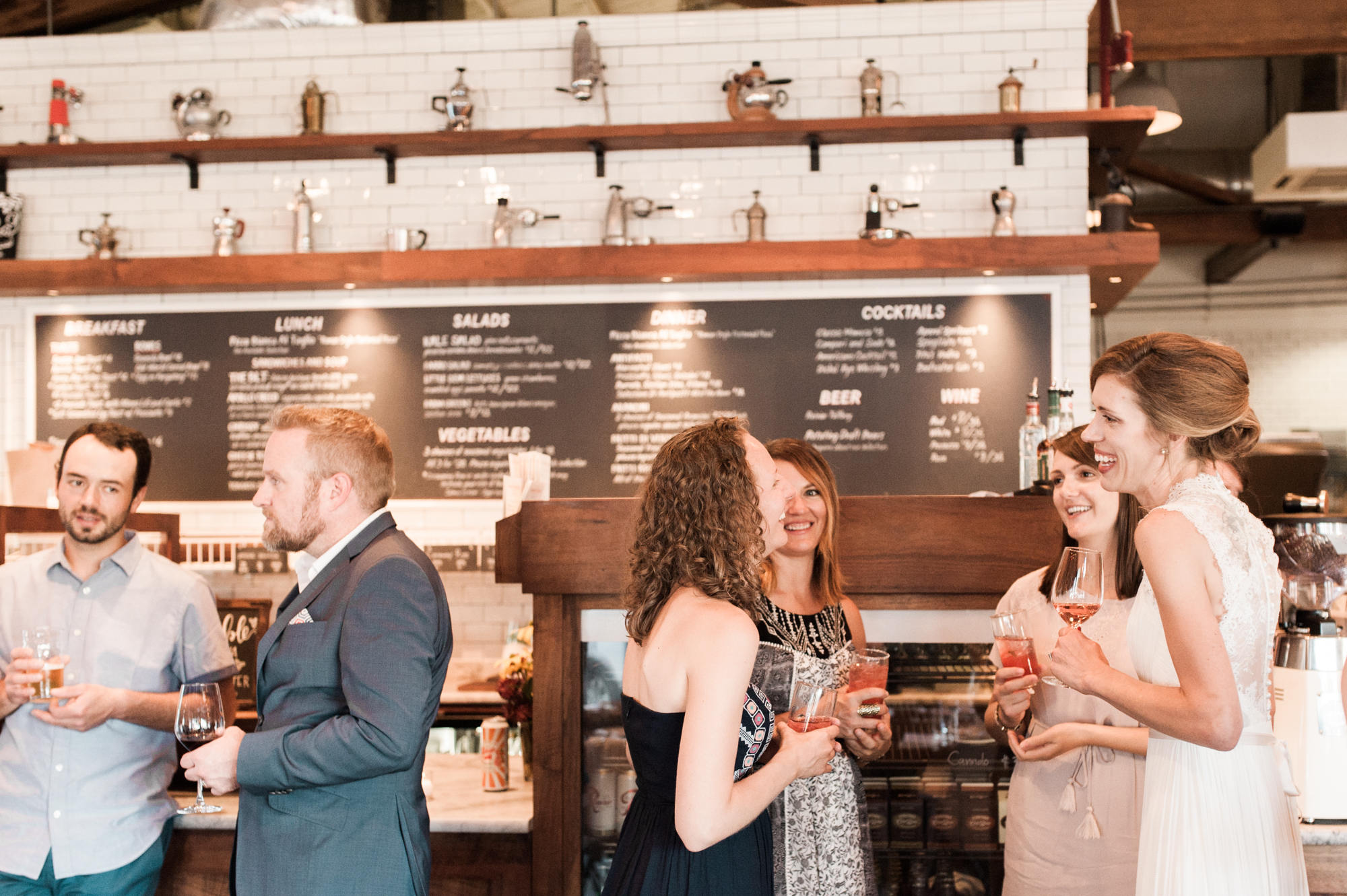 Wedding guests chat before dinner at Roman Candle Baking Co in Portland, Oregon. By wedding photographer Briana Morrison