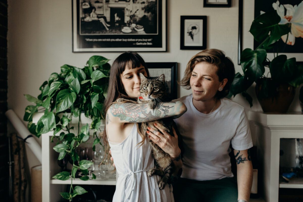 North Park San Diego engagement session of same sex couple in their home with their cat and lot sof plants.