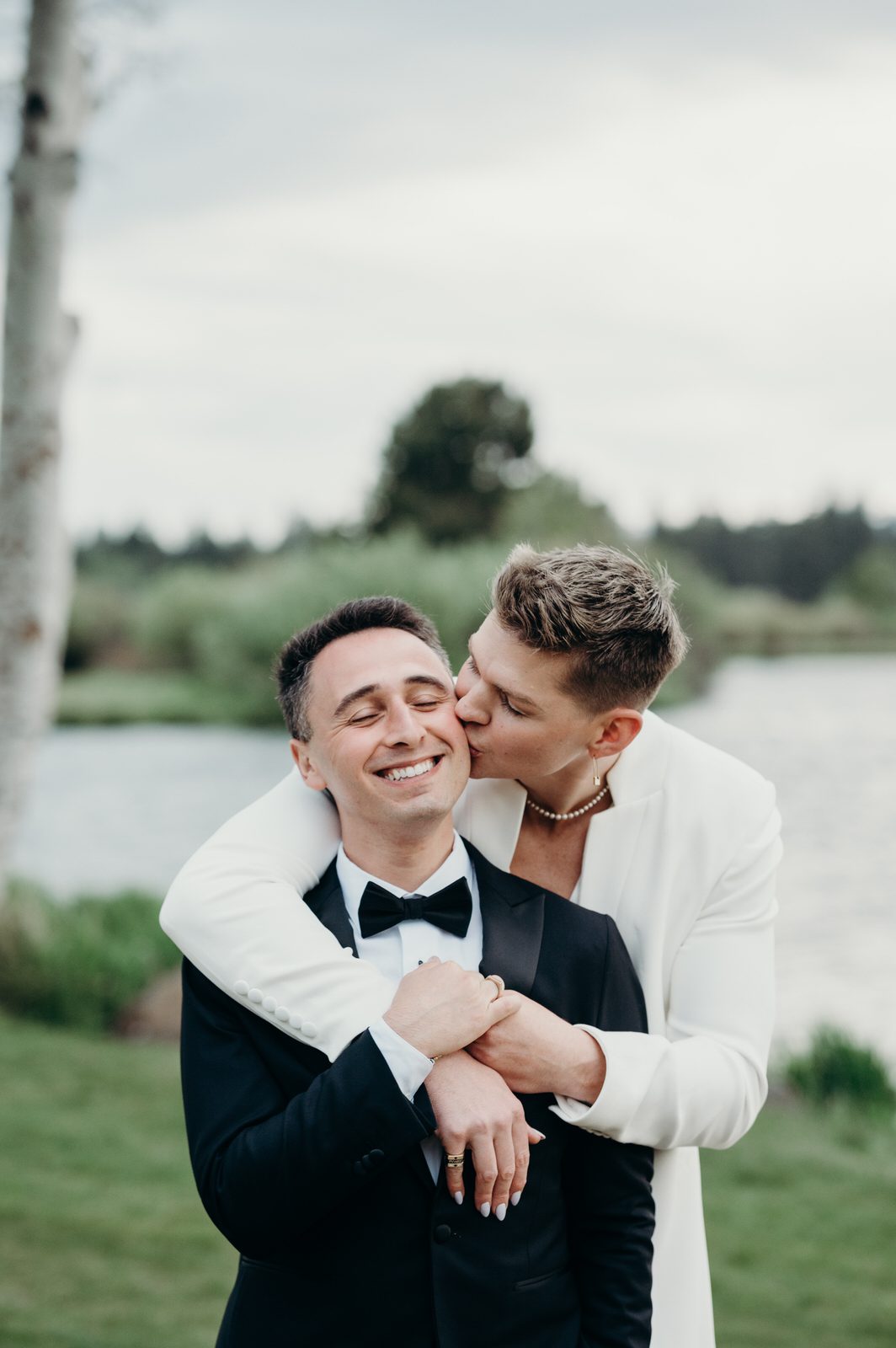 Two grooms snuggle up on their wedding day with smiles on their faces. Photographed by Portland wedding photographer, Briana Morrison.