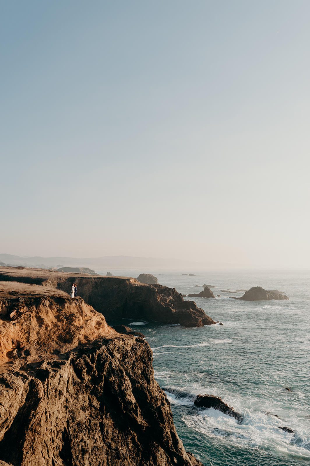 Beautiful ocean cliff landscape with bride and groom captured by Portland wedding photographer, Briana Morrison