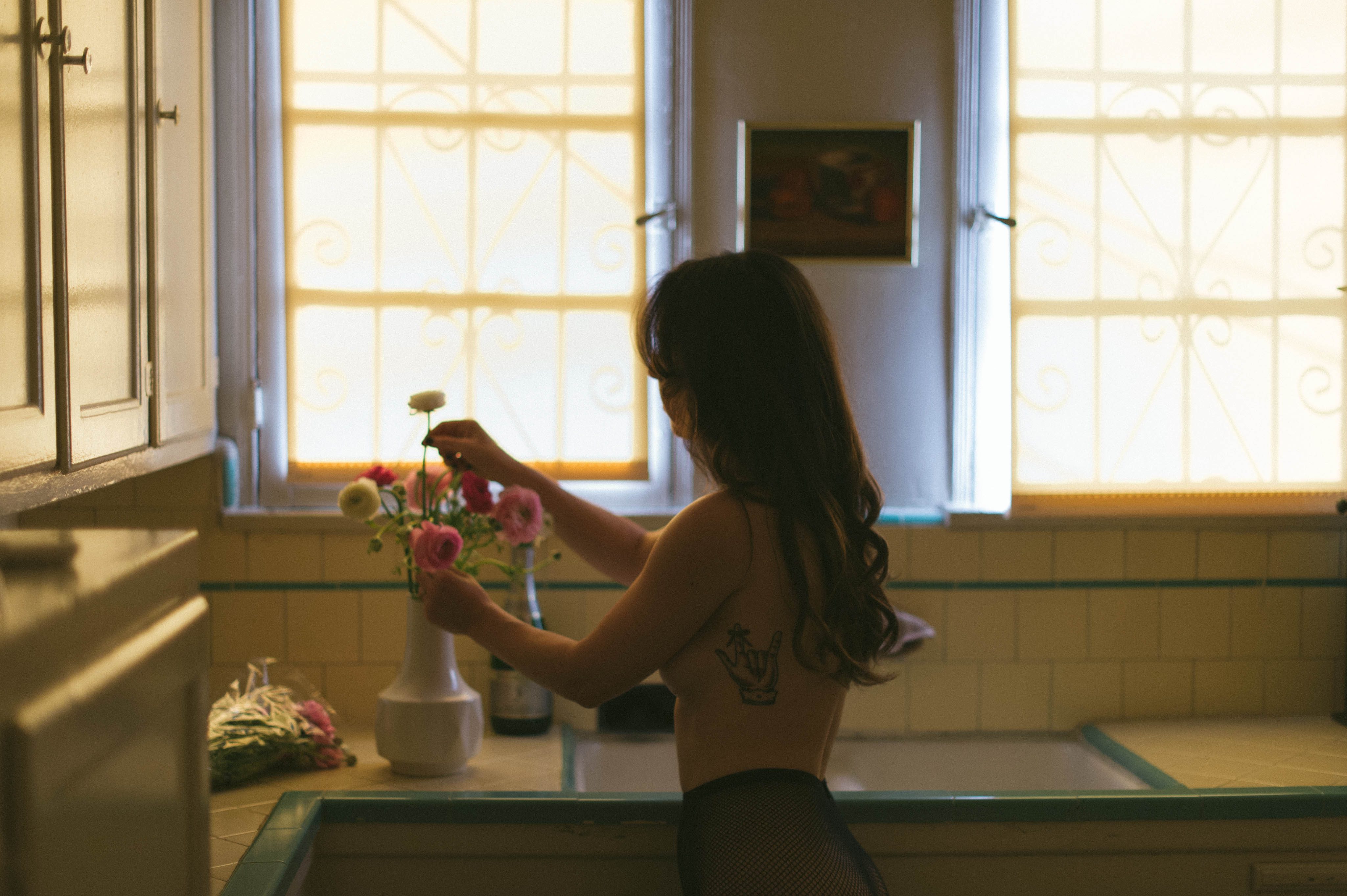 A topless woman arranging flowers. West Coast Boudoir Photography by Briana Morrison