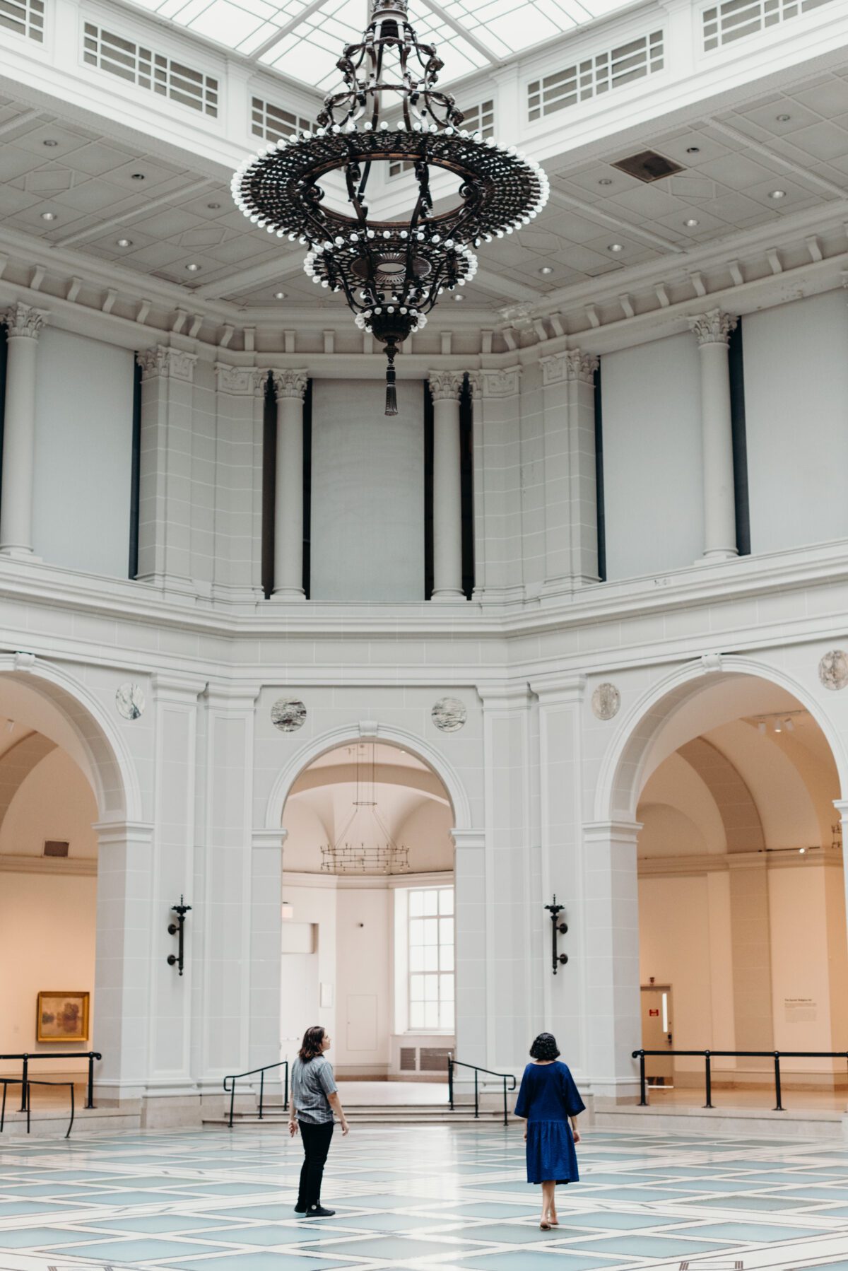 A wide frame image of the lobby inside of Brooklyn Museum with a man and woman standing inside for their Brooklyn NY engagement session