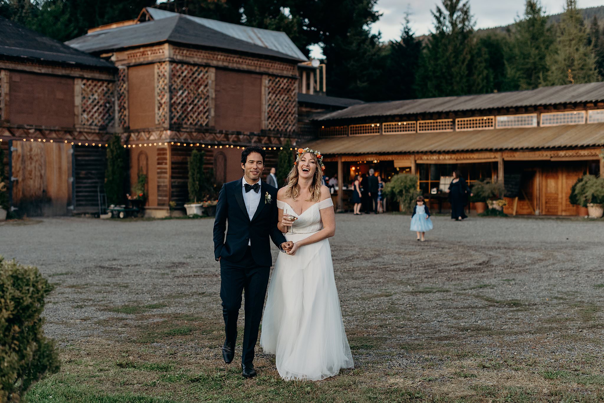 A bride and groom laugh, walking away from their Mt. Hood Organic Farms wedding venue and towards the camera.