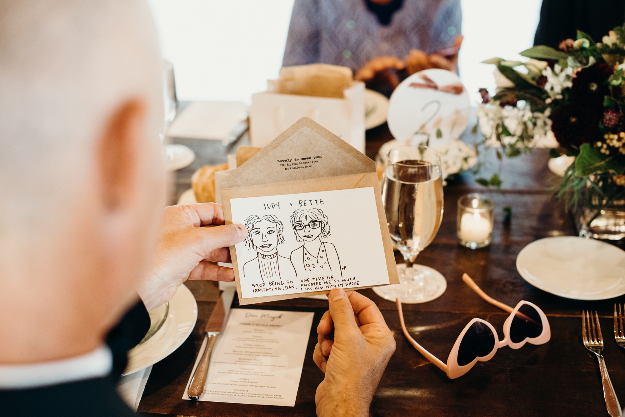 The groom admires an illustrated portrait of his sisters. Bad Portraits by Karlee Patton