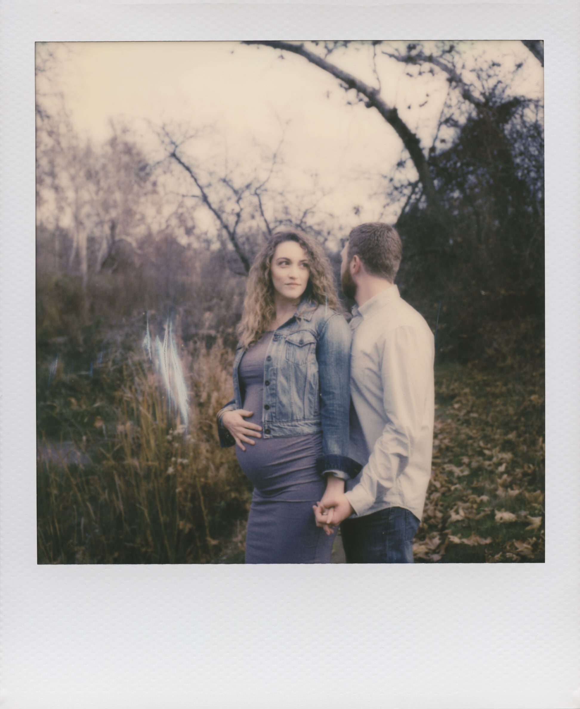 Portland family photographer takes a polaroid of a pregnant couple int he midst of winter.