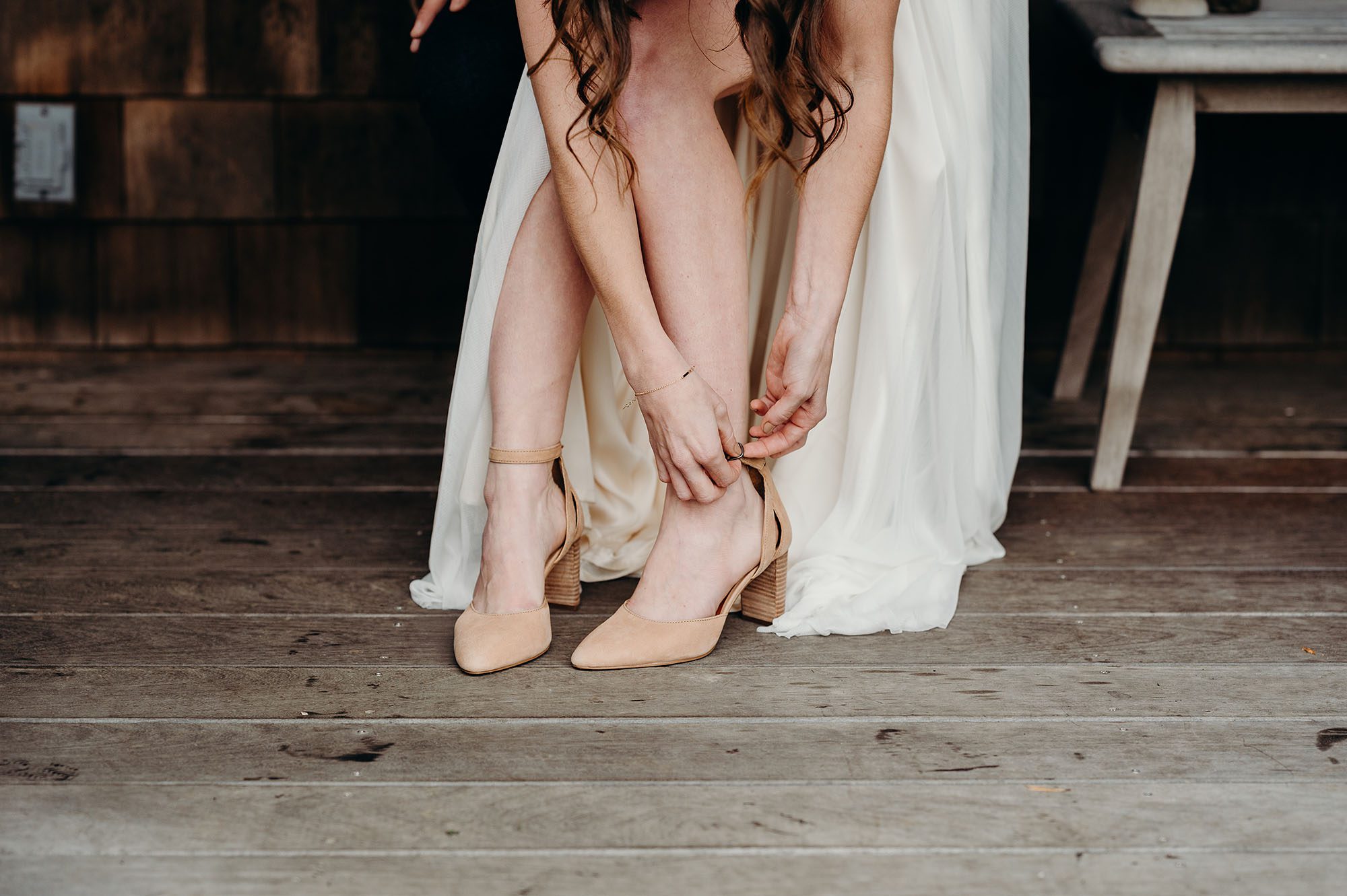 Bride Putting Shoes on before Ceremony by Briana Morrison Photography