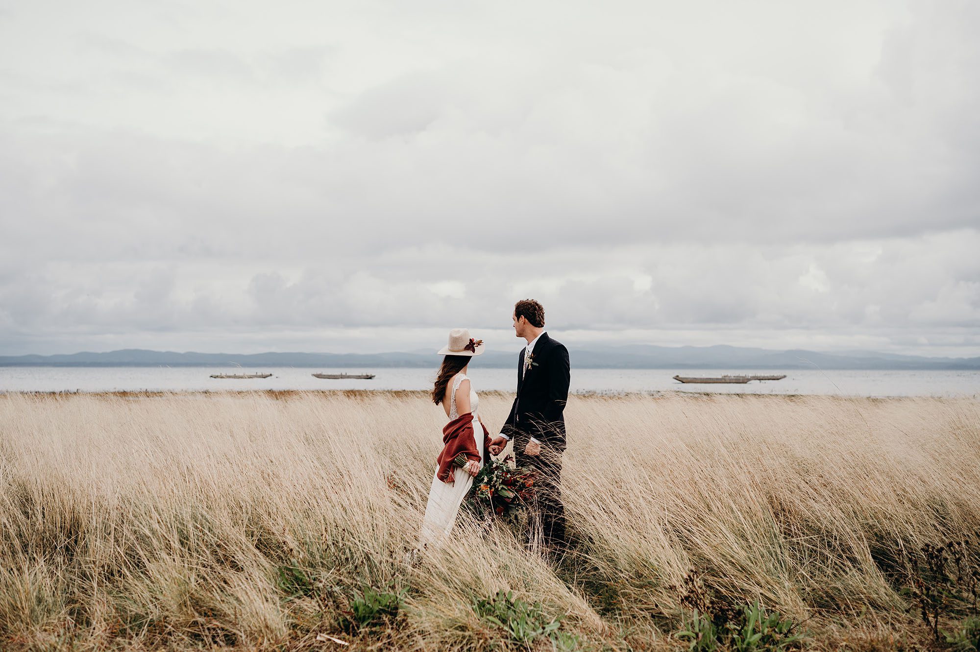 Bride & Groom Looking at the Water from the Dunes by Briana Morrison Photography