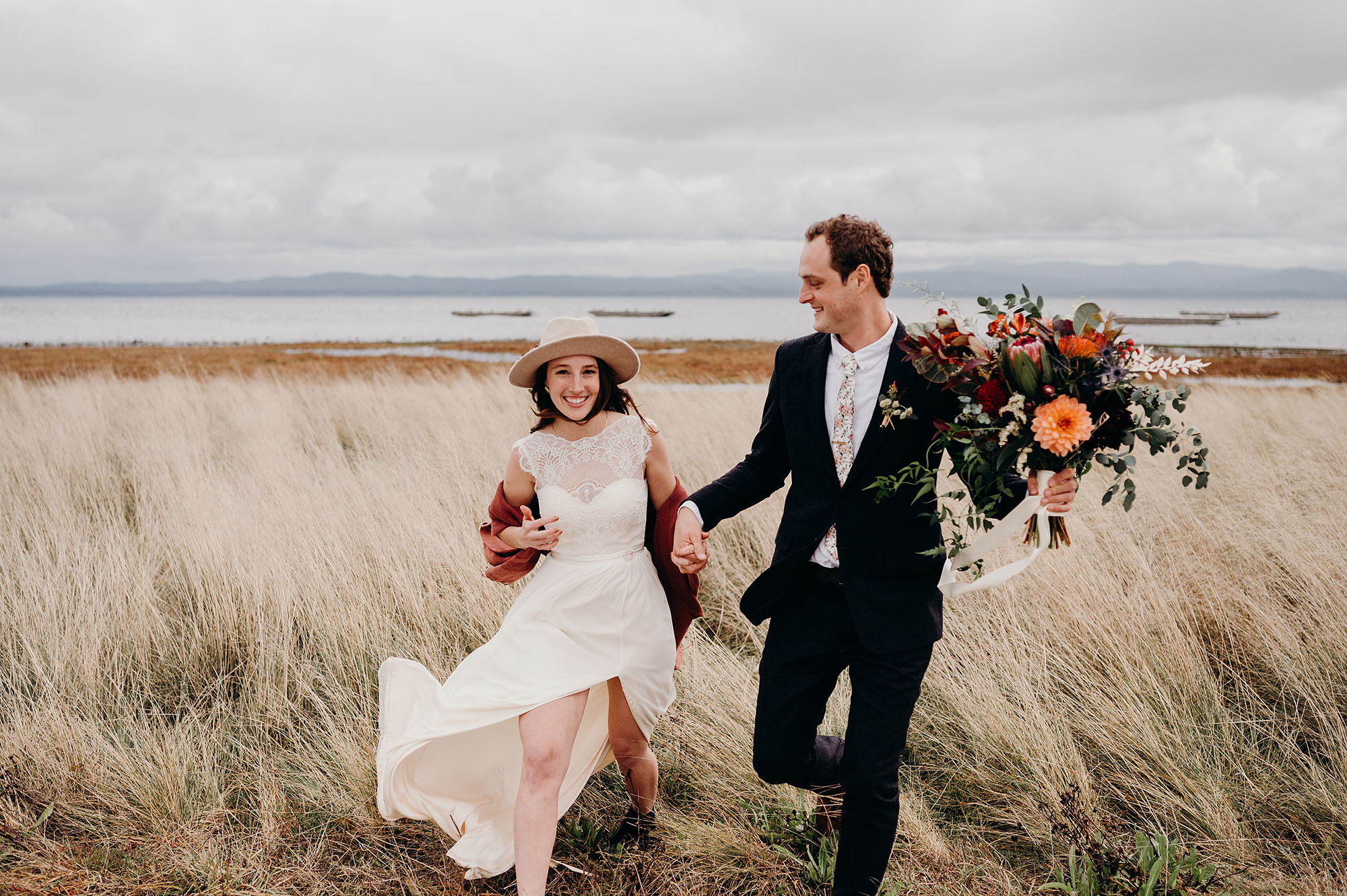 Bride & Groom Walking through the Dunes by Briana Morrison Photography