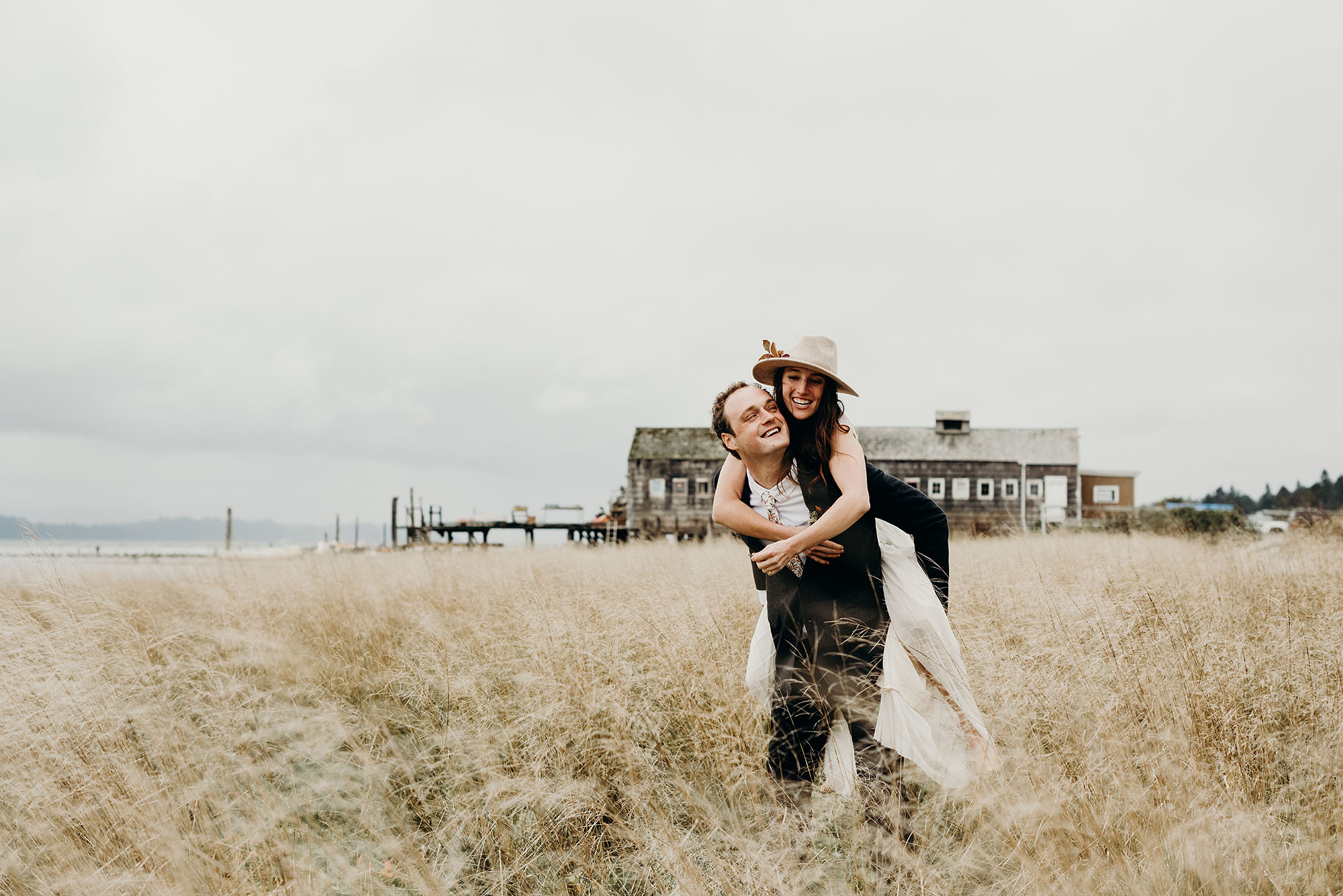 Groom Giving Bride a Piggyback Ride on the Beach by Briana Morrison Photography