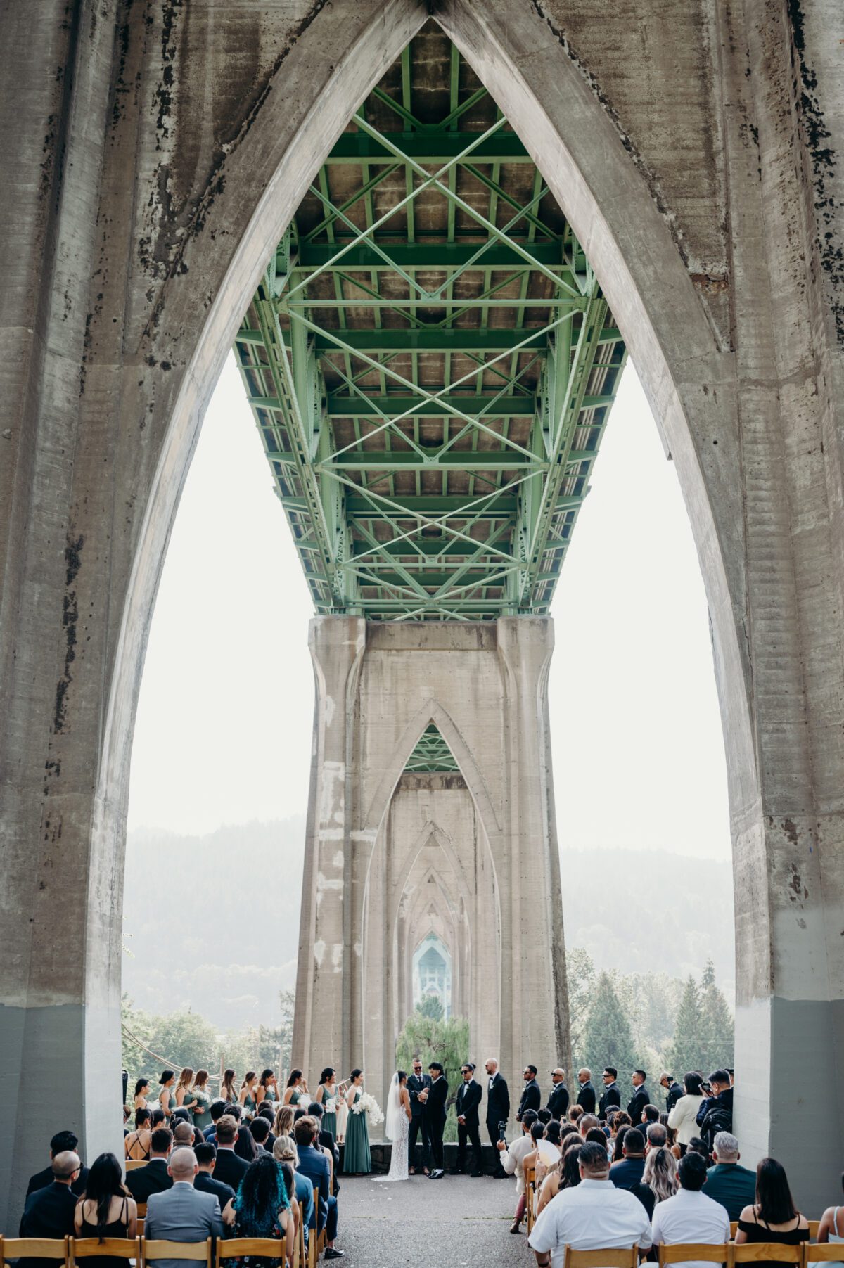 A large wedding gathering underneath the Cathedral Park / St. Johns bridge.