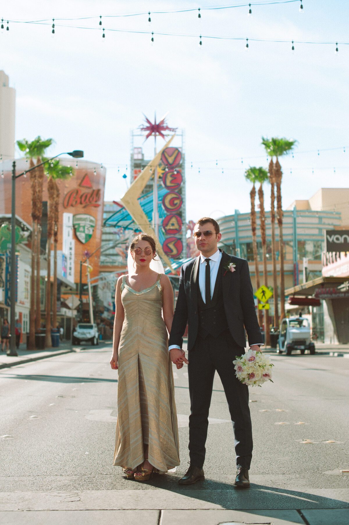 Las Vegas Elopement photographer captures a stylish couple posing in front of a vintage Vegas sign.
