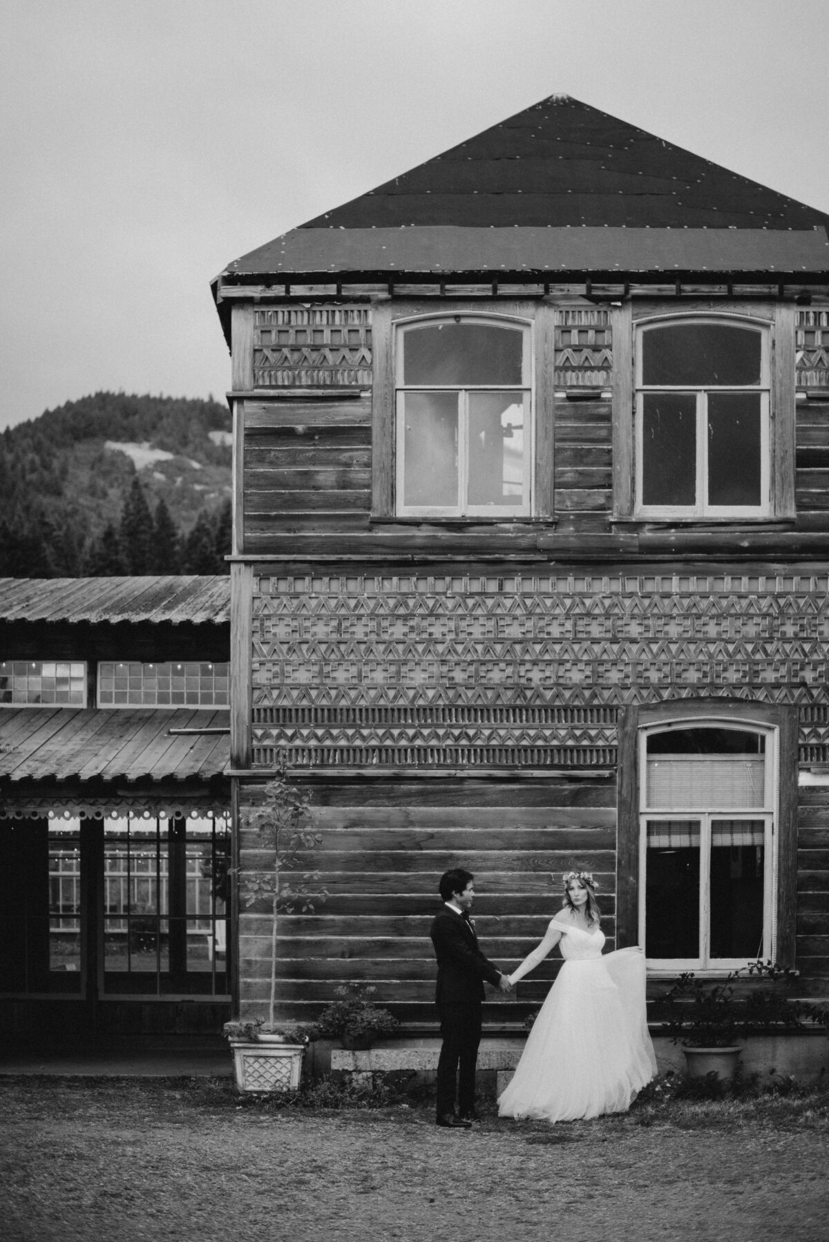 Black and white portrait of the bride and groom walking in front of the mt hood organic farms event space with mountains in the background