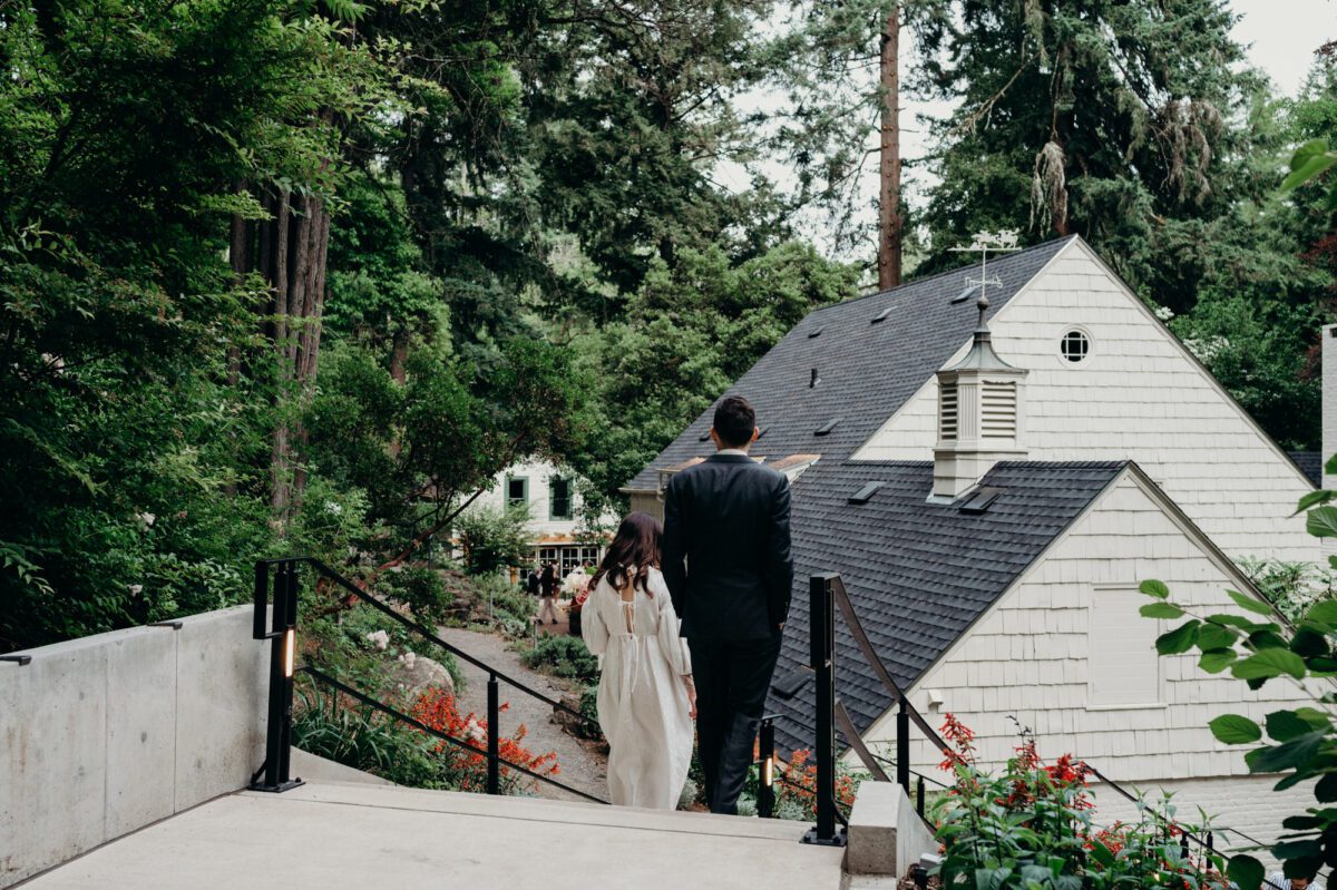 A bride and groom walk into their wedding reception at Leach Botanical Garden in Portland, Oregon.