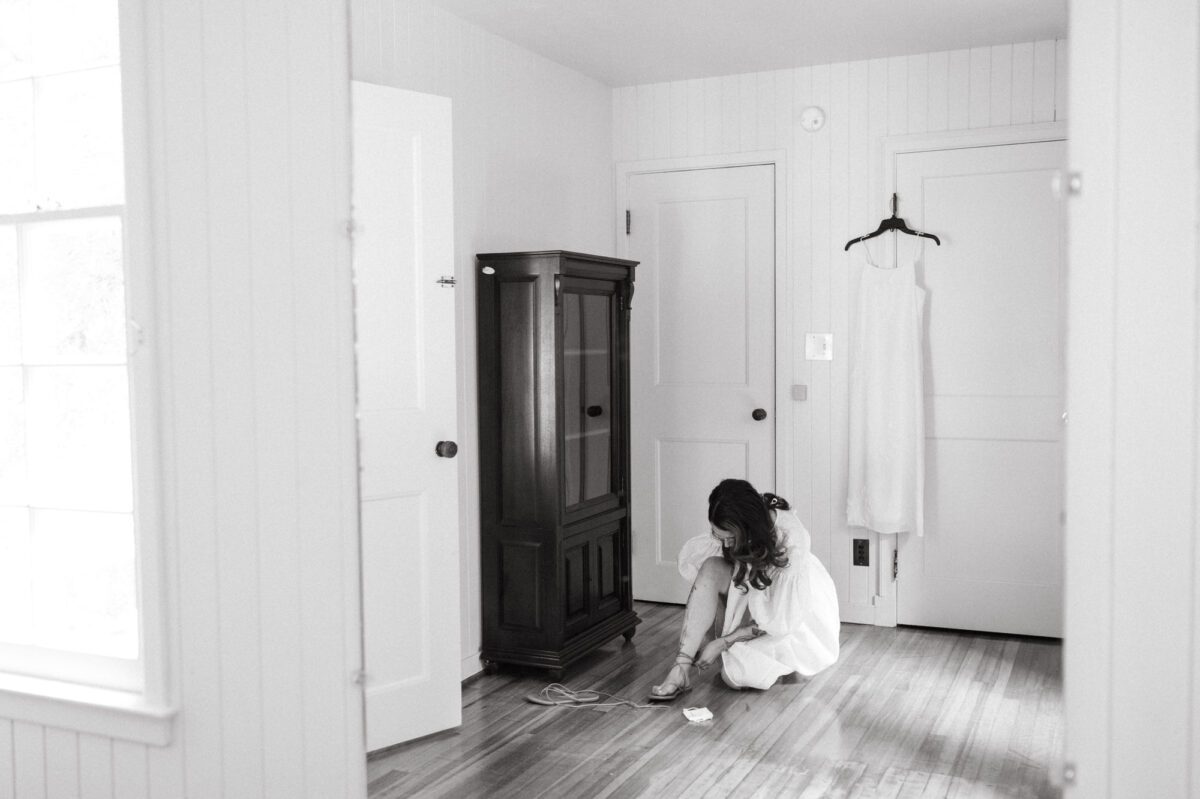 A black and white film photograph of a bride getting ready in the house at Leach Botanical Garden in Portland, Oregon.