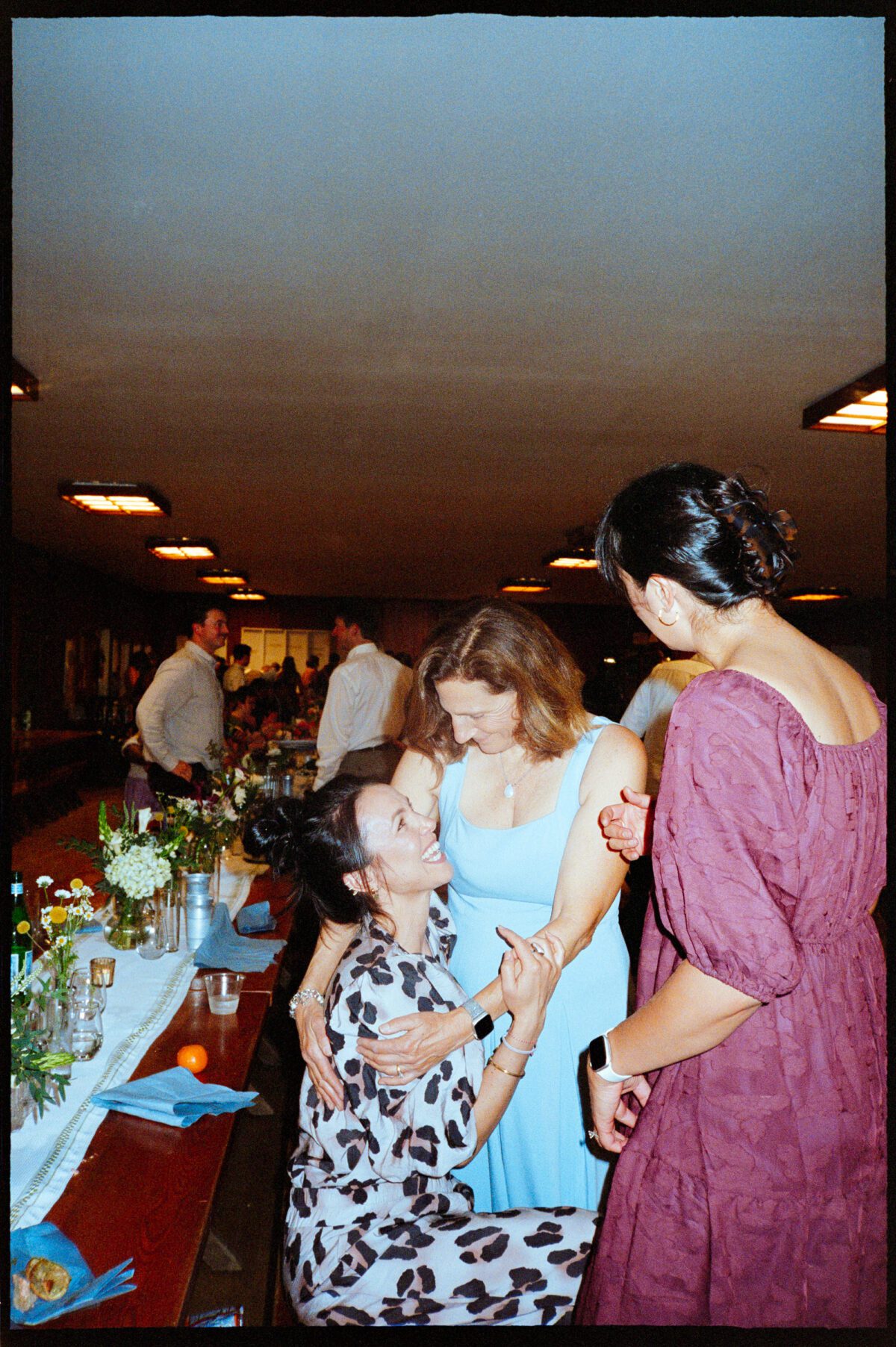 Guests connect and laugh together in the dining hall during a summer camp wedding at Camp Namanu. Photographed on film by Portland wedding photographer, Briana Morrison
