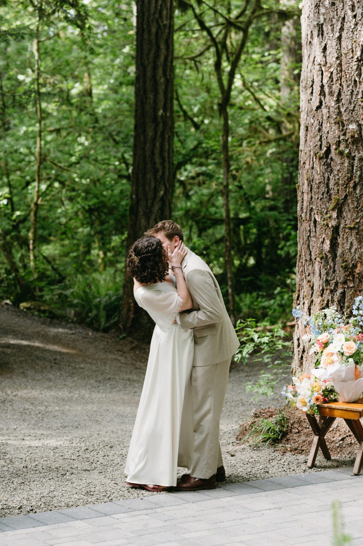 A bride and groom have their first kiss during the ceremony of their summer camp wedding. Photography by Briana Morrison