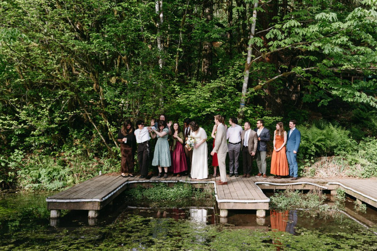 Friends gather on the dock of the duck pond at Camp Namanu for a group photo. Documentary wedding photography by Briana Morrison