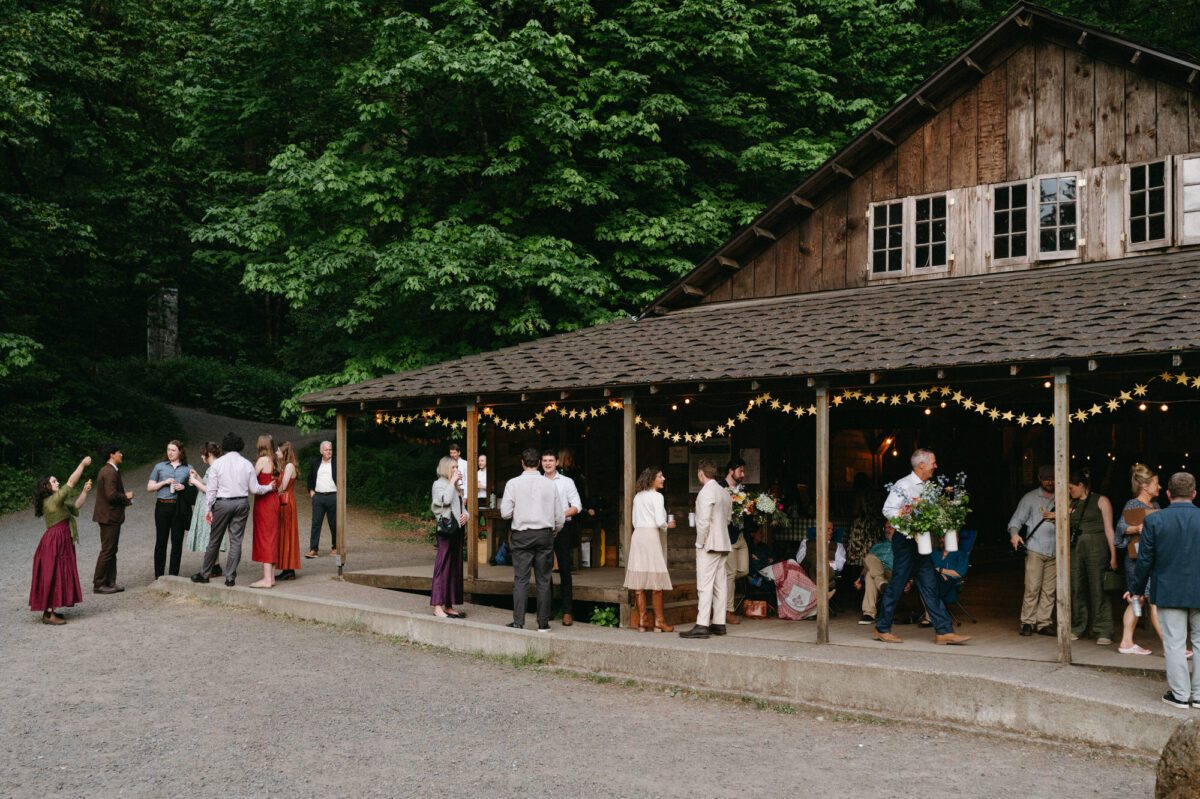 Guests gather in front of Uncle Toby's Storyhouse during this Camp Namanu wedding in Sandy, Oregon. Photography by Briana Morrison